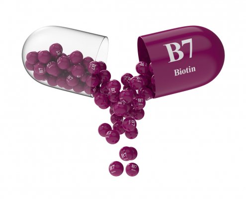 Open capsule with biotin from which the vitamin composition is pouring