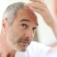 An lder man who is suffering from hair loss looking in the mirror and thinking about undergoing a FUT Treatment.