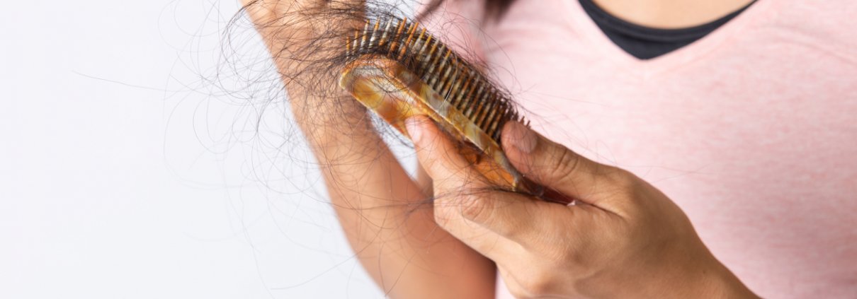 Woman looking at her hair fall out in a brush