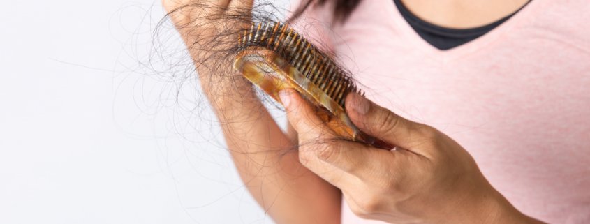Woman looking at her hair fall out in a brush